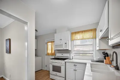 a kitchen with white cabinets and a stove top oven at Cozy Modern 2BR 1BA near LAX, LMU, SoFi Stadium and the Beach in Los Angeles