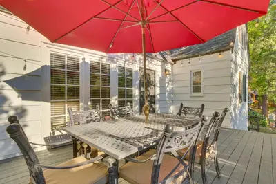 a table and chairs with a red umbrella on a deck at Private Dock on Lake Arrowhead! Cozy Mtn Cabin in Lake Arrowhead