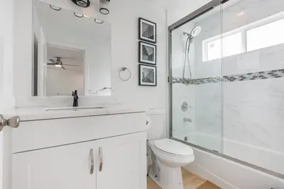 a white bathroom with a shower and a toilet at Minimalist Serene Home near Rose Bowl Stadium in Pasadena