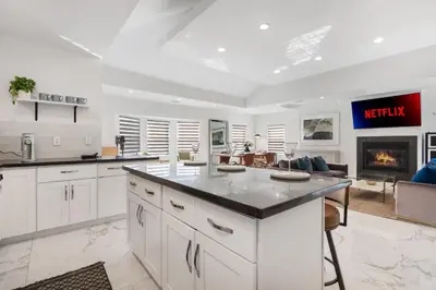 a kitchen with white cabinets and a living room at Minimalist Serene Home near Rose Bowl Stadium in Pasadena