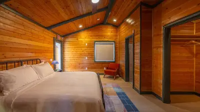 a bedroom with a bed and a chair in a room at Arkouda Stays in Big Bear Lake