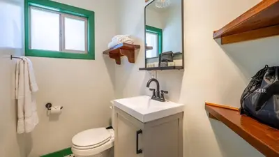 a bathroom with a sink and a toilet and a mirror at Arkouda Stays in Big Bear Lake