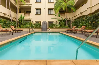 a swimming pool in front of a building with chairs at Modern 1Bed in Koreatown- Pool, Sauna & Free Parking in Los Angeles