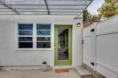 a white house with a green door and a fence at 3 Mi to Old Pasadena Cozy Couples Studio with Pool in Pasadena