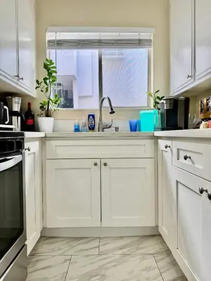 a kitchen with white cabinets and a sink and a window at Proper Stays at Melrose - West Hollywood Premium E suite in Los Angeles