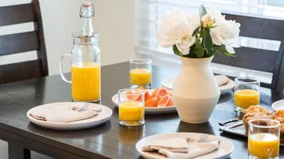 a table with plates of orange juice and a vase of flowers at Sunny Venice Beach Home with Open Living Walkability to Abbot Kinney Venice Drift by AvantStay in Los Angeles