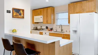 a kitchen with a white refrigerator and wooden cabinets at Sunny Venice Beach Home with Open Living Walkability to Abbot Kinney Venice Drift by AvantStay in Los Angeles