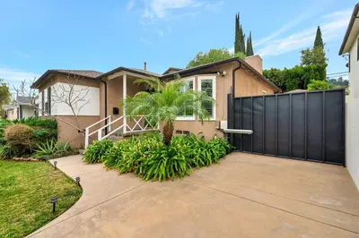 a house with a black fence and a palm tree at Charming 3BR with Ping-Pong and Spa!