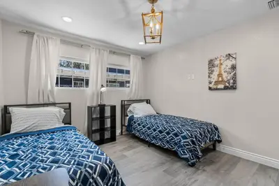 a bedroom with two beds and a chandelier at Wonderful Home Near Claremont! With Amazing Backyard! in Pomona