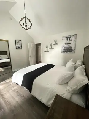 a bedroom with a large white bed and a chandelier at Woodsy Chic Family-Friendly Spacious Getaway in Lake Arrowhead