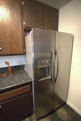 a stainless steel refrigerator in a kitchen with wooden cabinets at Charming 1-bedroom apartment in amazing Palms, Los Angeles with AC, Parking in Los Angeles