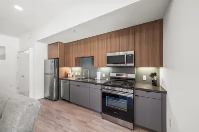 a kitchen with stainless steel appliances and wooden cabinets at Stylish Condo Mins to Shoreline in Long Beach