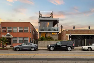 three cars parked in a parking lot in front of a building at Hip Venice 5BR 4BA Home w Rooftop and Steps to the Beach in Los Angeles