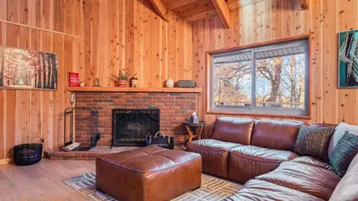 a living room with a leather couch and a fireplace at 5BDR Hot Tub Deck Firepit Mins to Village Lake The Hilltop by AvantStay in Lake Arrowhead