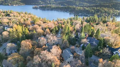 an aerial view of a house with trees and a lake at 5BDR Hot Tub Deck Firepit Mins to Village Lake The Hilltop by AvantStay in Lake Arrowhead