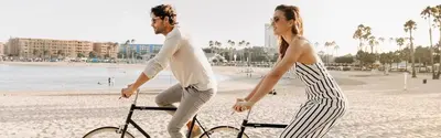 a man and a woman riding a bike on the beach at Amethyst Sky Loft - Elevated Two-Story Waterfront in Los Angeles