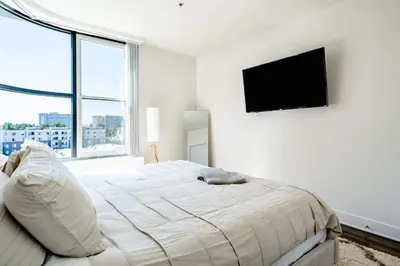a white bedroom with a bed and a flat screen tv at Sleek Marina Den Central Gym Pool King Bed in Los Angeles