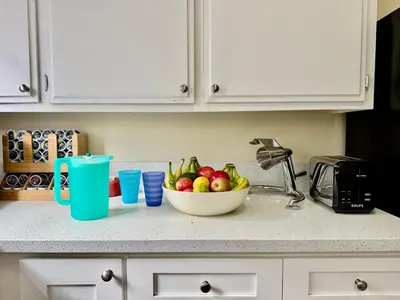 a bowl of fruit on a kitchen counter with a sink at Proper Stays at Melrose - West Hollywood Premium M suite in Los Angeles