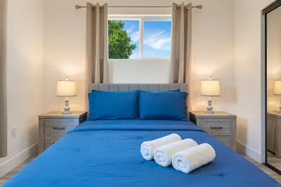 a bedroom with a blue bed with two towels at The Harvard Modern Retreat LA in Los Angeles
