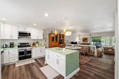 a kitchen with white cabinets and a living room at Elsa House in Warner Center Plaza One Heliport