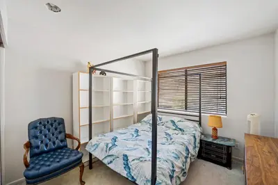 a bedroom with a bed and a blue chair at Elsa House in Warner Center Plaza One Heliport