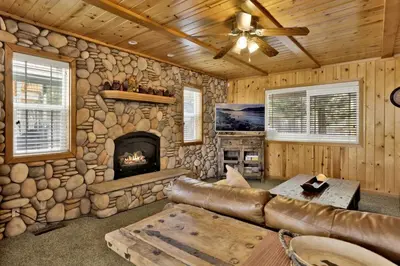 a living room with a couch and a stone fireplace at Brownie Resort Your Walk-to-Summit Getaway Family's Snowboarders Skiers in Big Bear Lake