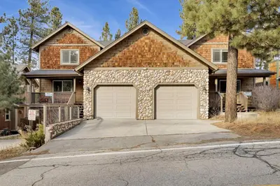 a brick house with two garage doors on a driveway at Brownie Resort Your Walk-to-Summit Getaway Family's Snowboarders Skiers in Big Bear Lake