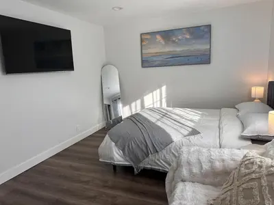 a white bedroom with a bed and a flat screen tv at Cozy Home near Beaches, LAX, SoFi, Intuit Dome,405 in Hawthorne