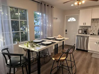a kitchen with a table and some chairs and a table and some windows at Cozy Home near Beaches, LAX, SoFi, Intuit Dome,405 in Hawthorne