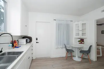 a white kitchen with two chairs and a table at Fully Furnished 1-Bedroom in Los Angeles