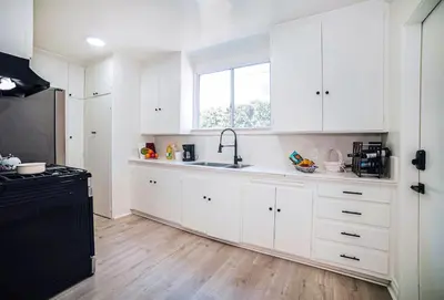a kitchen with white cabinets and a sink and a window at Fully Furnished 1-Bedroom in Los Angeles