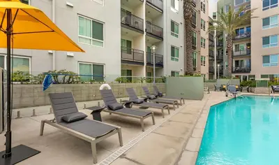a pool with lounge chairs and an umbrella next to a building at BOHO Style Home LA -Free Parking 10min To Cedars in Los Angeles