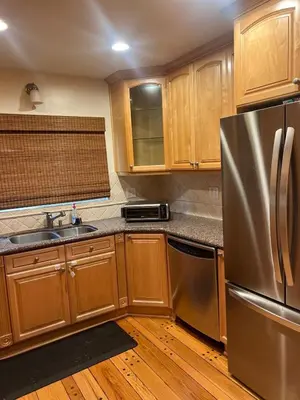 a kitchen with wooden cabinets and a stainless steel refrigerator at Cozy Home in Picturesque LA Near Major Attractions
