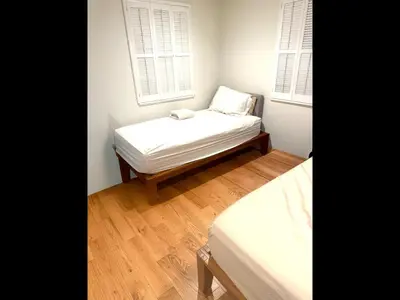 a small bedroom with a bed and two windows at Cozy Home in Picturesque LA Near Major Attractions