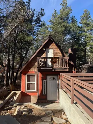 a small house with a porch and a balcony at Snuggle Inn Cabin in Running Springs