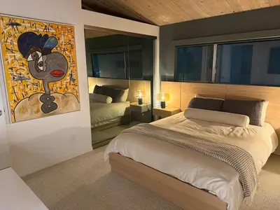 a bedroom with a bed and a painting on the wall at Hillside Luxury MidCentury Modern Spa Retreat View in Los Angeles