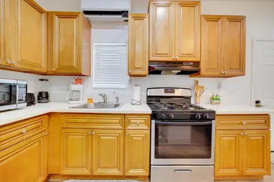 a kitchen with wooden cabinets and a stove top oven at Work and Play! Studio Retreat 2 Mi to Dtwn Riverside in Riverside