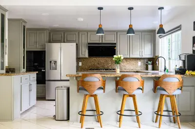 a kitchen with white cabinets and wooden bar stools at Cozy Full Suite Private Bathroom Quiet Stay in Norwalk