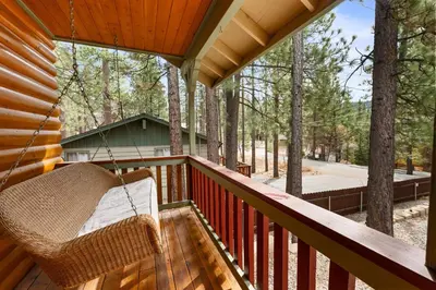 a porch with a hammock on a log cabin at Leaf & Needle - Walk to Lake & Village, Picnic Table, Single Story, Fenced Yard in Big Bear Lake