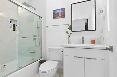 a white bathroom with a toilet and a glass shower at New Family House Fanstic View Azusa in Azusa