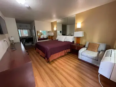 a hotel room with a bed and a chair at Sierra Inn in South El Monte