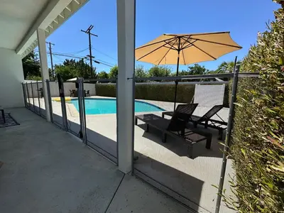 a patio with a chair and an umbrella next to a pool at Modern 3BR with King Bed, Gated Pool and BBQ Oasis in West Valley Area Heliport