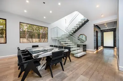 a dining room with a glass table and stairs at Ultra Luxe Estate With Pool and Stunning 360 LA Views in Los Angeles