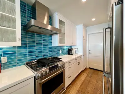 a kitchen with white cabinets and a stove top oven at Malibu Waterfront Gallery with Private Beach Access in Malibu Beach