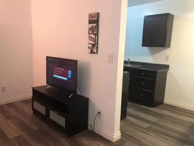 a living room with a flat screen tv on a stand at Modern 1 Bedroom Hollywood Apartment Near Larchmont Village Walk of Fame and Studios in Los Angeles