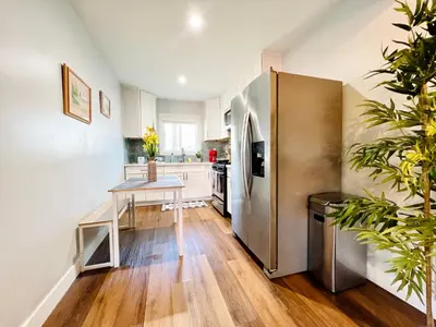 a kitchen with a table and a stainless steel refrigerator at Golden Downey Designer Abode - Poolside Suite in Downey