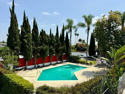 a swimming pool in a garden with trees at Golden Downey Designer Abode - Poolside Suite in Downey