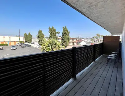 a balcony with a black fence and a view of a parking lot at Golden Downey Designer Abode - Poolside Suite in Downey