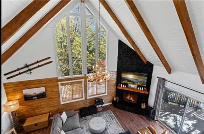 a living room with a fireplace and a large window at Relaxing 4 bedroom Mountain Stay in Lake Arrowhead