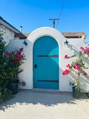 a green door on a white building with pink flowers at Ojai Serenity Retreat in Ojai
